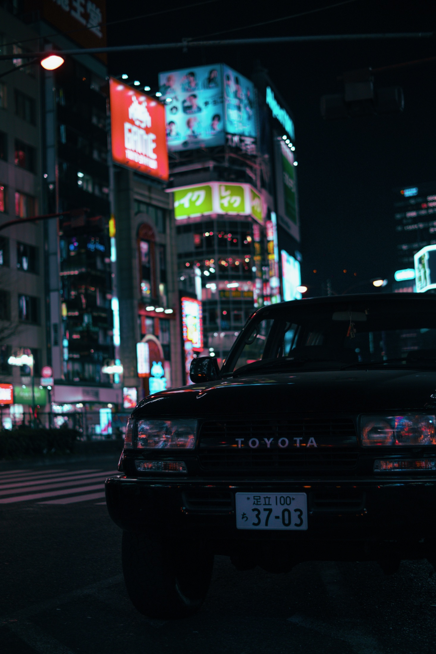 Toyota sedan parked on a neon-soaked street at night